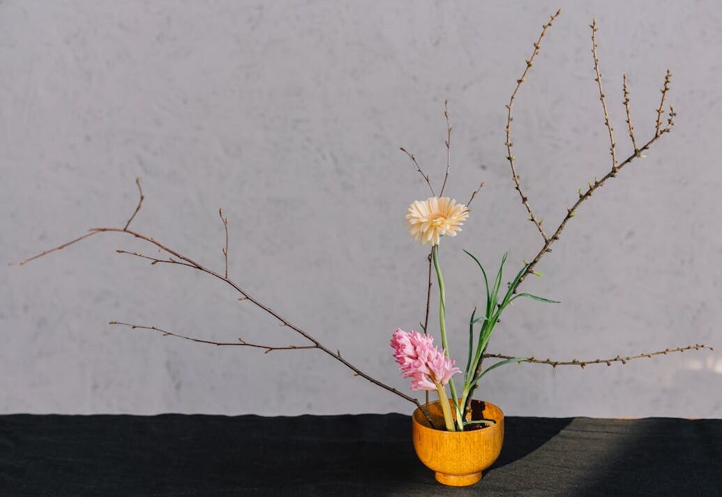 A serene minimalist floral arrangement in a wooden vase with branches and blooms