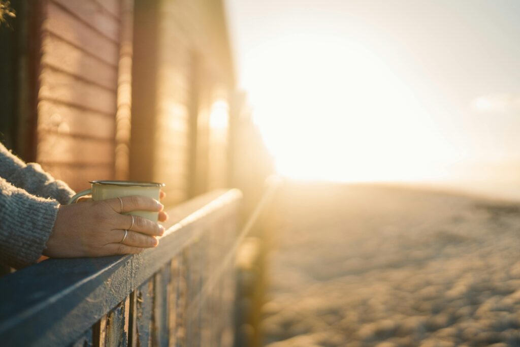 A serene morning scene with a hand holding a mug at sunrise capturing warmth and tranquility